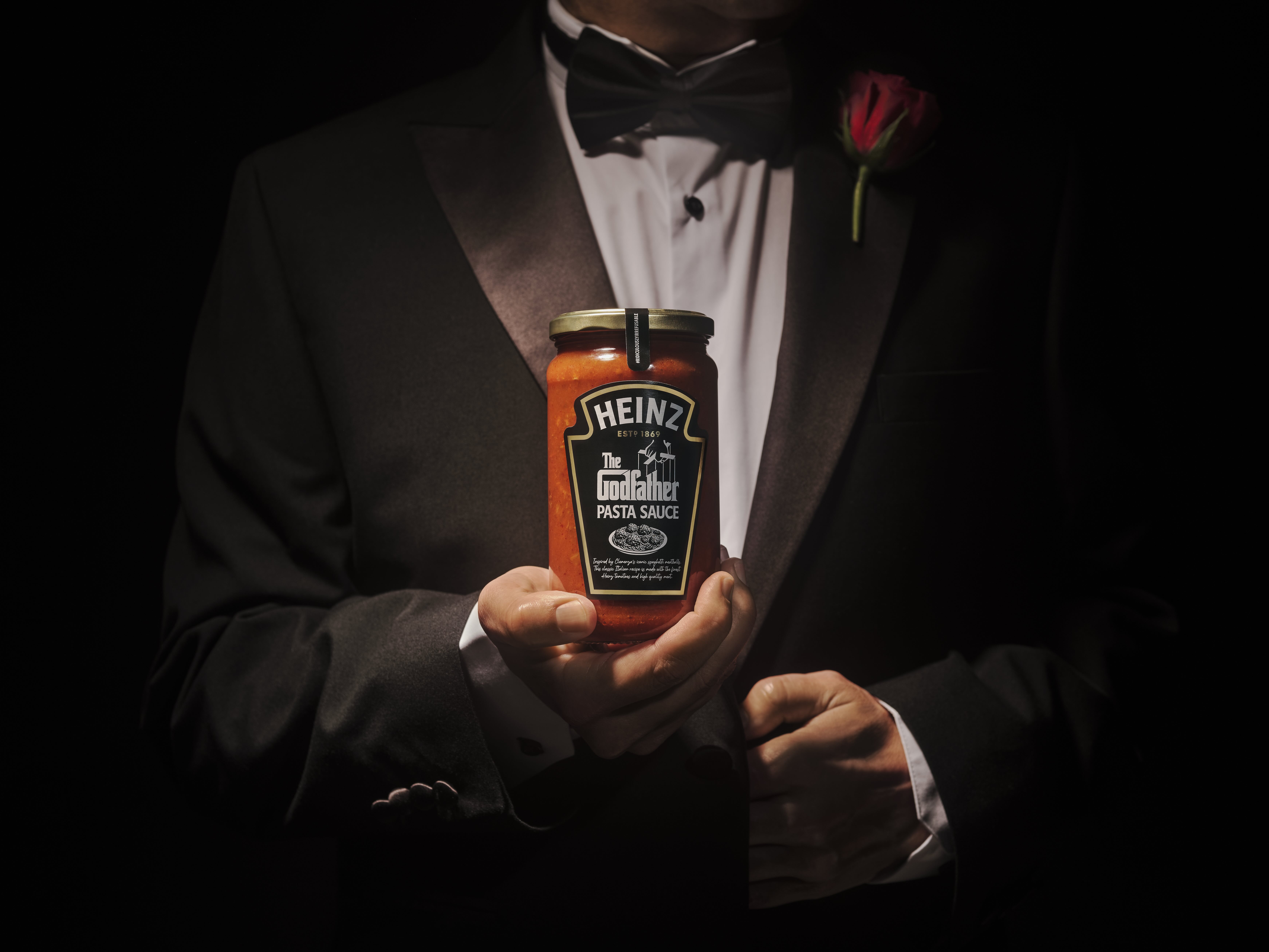 Man in black suit holding Heinz & The Godfather Pasta Sauce